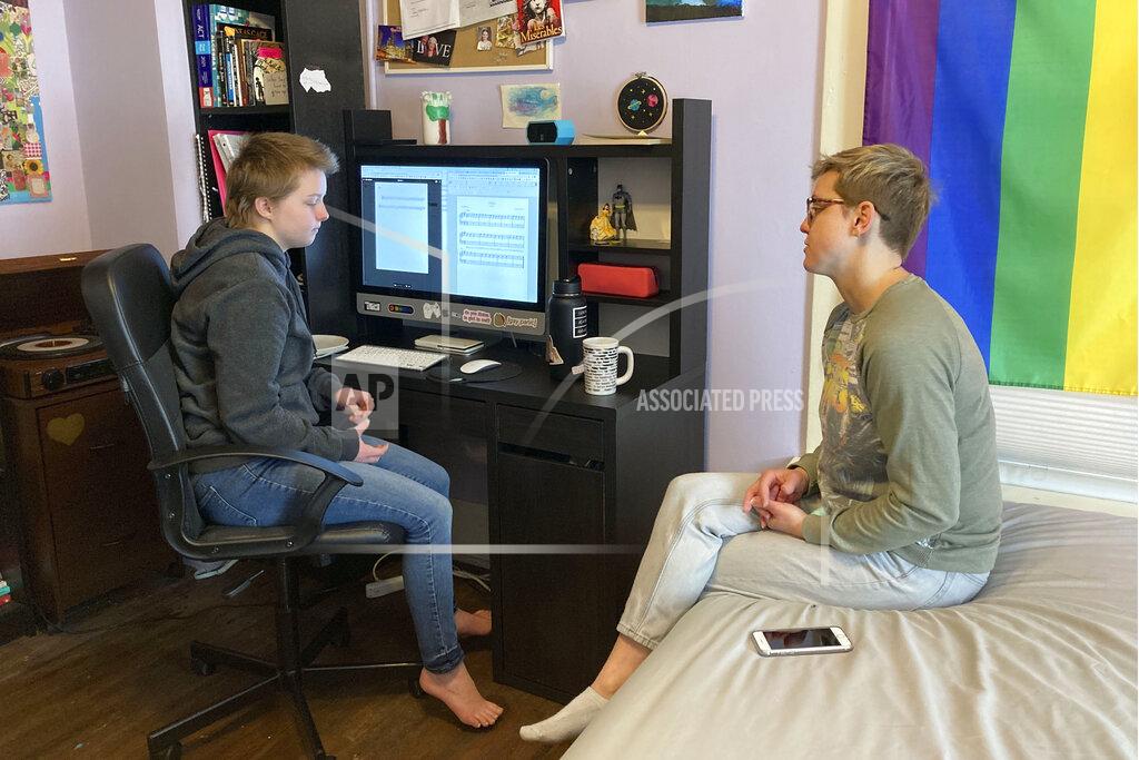 Kantele Franko Graciela Leahy, 13, an eighth grader at Ohio's Columbus Gifted Academy, talks with her mother, Elisa Leahy, right, in her bedroom, in Columbus, Ohio, Tuesday, Feb. 23, 2021. A year later in the pandemic, the unplanned experiment with distance learning continues for thousands of students like Leahy who have yet to set foot back in classrooms. (AP Photo/Kantele Franko)