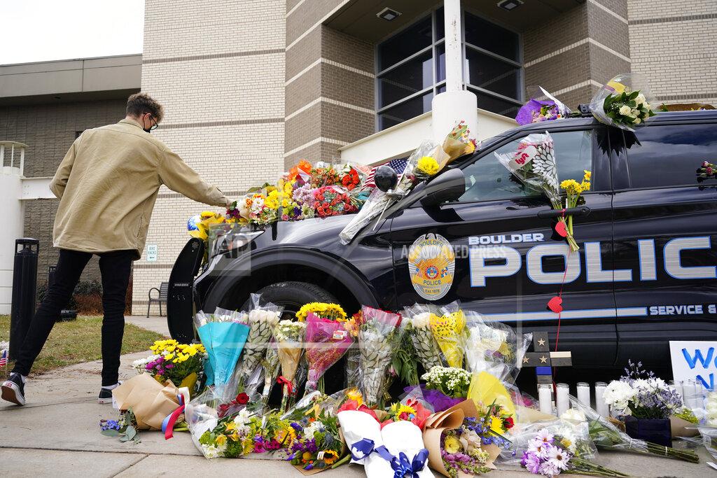 David Zalubowski In this March 23, 2021, photo, a man leaves a bouquet on a police cruiser parked outside the Boulder Police Department after an officer was one of the victims of a mass shooting at a King Soopers grocery store in Boulder, Colo. The suspects in the most recent shooting sprees found it relatively easy to get their guns. The suspect in the shooting at a Boulder supermarket was convicted of assaulting a high school classmate but still got a gun.(AP Photo/David Zalubowski)
