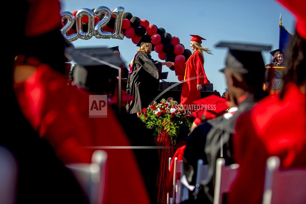 Jake May Grand Blanc senior Cassidy Young receives her diploma as more than 600 students graduate during one of two commencement ceremonies held on Thursday, June 3, 2021 at Frank Thomas Field in Grand Blanc, Mich. (Jake May/The Flint Journal via AP)