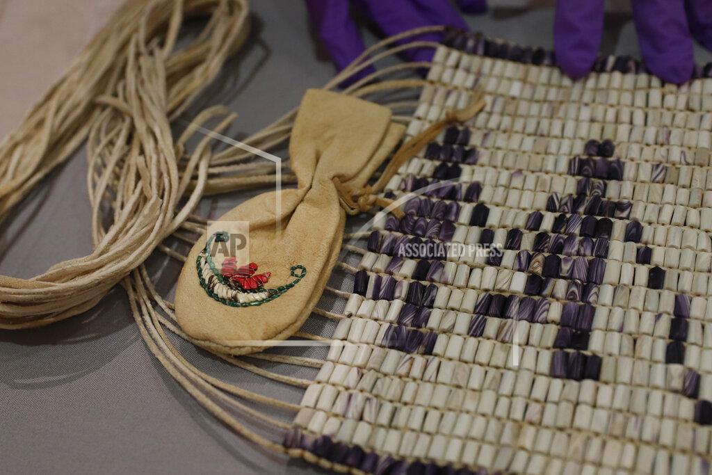 Co-curator Jo Loosemore examines a recently created wampum belt made by members of the Wampanoag Native America people, after its unpacking and prior to it going on display in Southampton, England, Thursday, Aug. 13, 2020. On the 400th anniversary of the Mayflower voyage, commemorations are focusing on both the Pilgrim settlers and the Native people whose lives were transformed by their arrival. An exhibition in England focuses on one casualty of colonization: a wampum belt taken from the Wampanoag people to England in the 17th century, and then lost. (AP Photo/Alastair Grant)