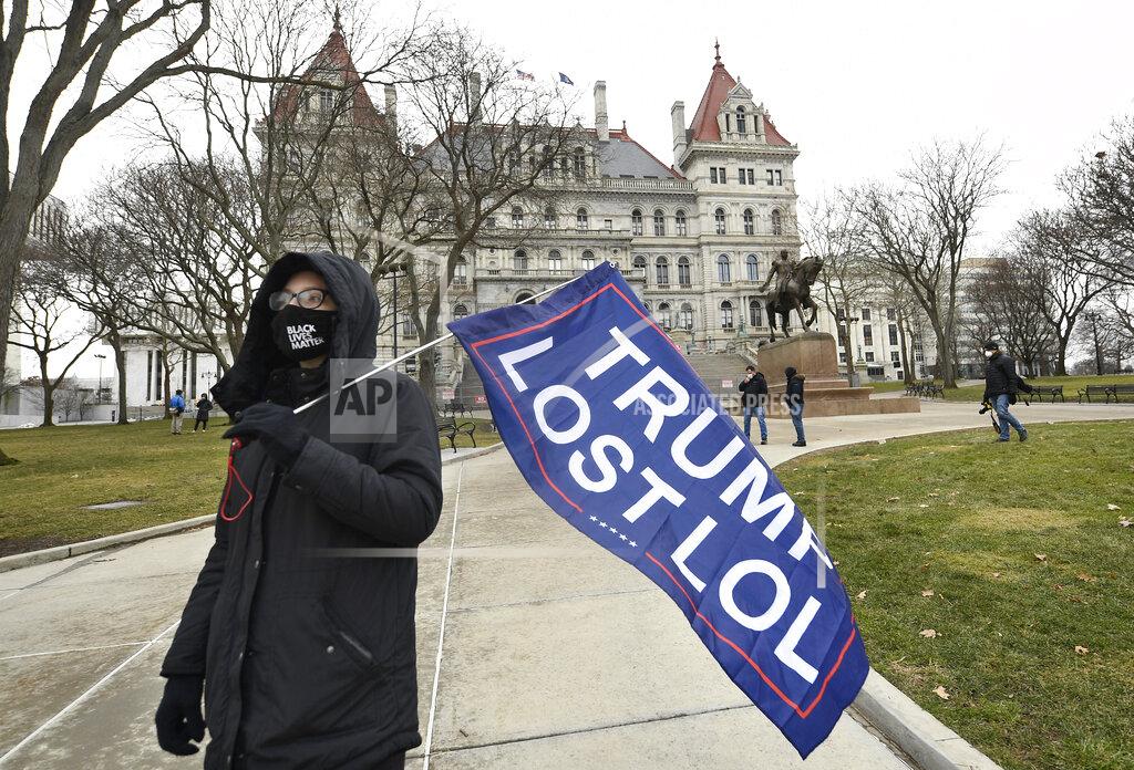 Hans Pennink Christina Janowitz of Guilderland, N.Y., from the group "All Of Us' holds a flag while counter-protesting a Trump rally ahead of the inauguration of President-elect Joe Biden and Vice President-elect Kamala Harris at the New York State Capitol Sunday, Jan. 17, 2021, in Albany, N.Y. (AP Photo/Hans Pennink)