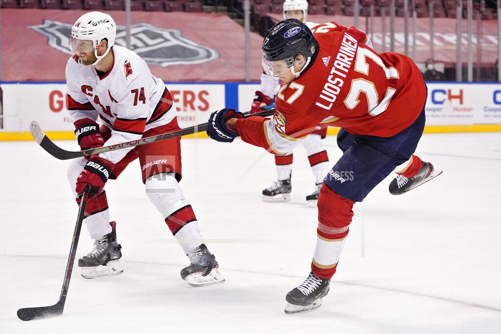 Wilfredo Lee Florida Panthers center Eetu Luostarinen (27) takes a shot against Carolina Hurricanes defenseman Jaccob Slavin (74) during the second period of an NHL hockey game, Monday, March 1, 2021, in Sunrise, Fla. (AP Photo/Wilfredo Lee)