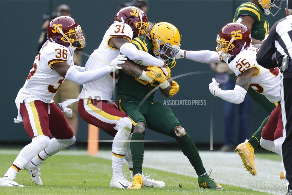 Matt Ludtke Green Bay Packers' Aaron Jones is stopped by Washington Football Team's Benjamin St-Juste (25), Kamren Curl (31) and Danny Johnson (36) during the first half of an NFL football game Sunday, Oct. 24, 2021, in Green Bay, Wis. (AP Photo/Matt Ludtke)