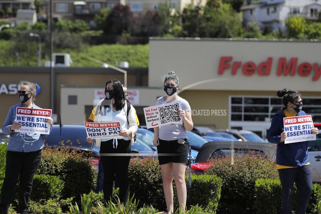 Ted S. Warren Members and supporters of the United Food and Commercial Workers International Union take part in a protest outside the Fred Meyer grocery store in Burien, Wash., against Fred Meyer's parent company Kroger, Friday, May 15, 2020. Kroger officials have said they are ending the additional $2 hourly "hero pay" bonus that had been paid to workers since late March during the coronavirus pandemic. The company said Friday it will now offer one-time bonus payments of $400 and $200 for full- and part-time employees to be paid in two installments. (AP Photo/Ted S. Warren)