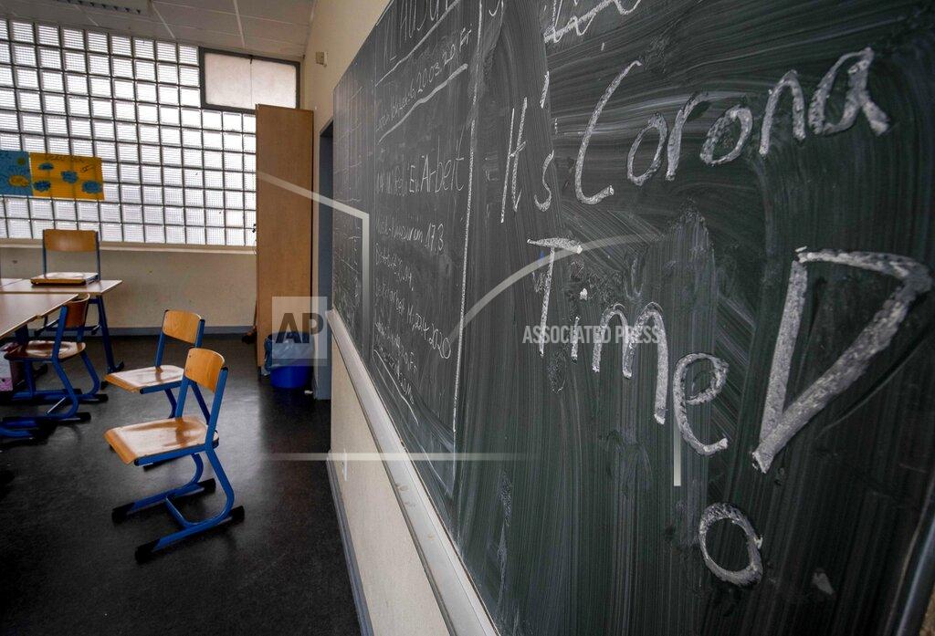FILE -- In this Friday, March 13, 2020 photo a slogan on a chalkboard reads 'It's Corona Time' in an empty class room of a high school in Frankfurt, Germany, March 13, 2020. As Germany’s 16 states start sending millions of children back to school in the middle of the global coronavirus pandemic, those used to the country’s famous “Ordnung” are instead looking at uncertainty, with a hodgepodge of regional regulations that officials acknowledge may or may not work. (AP Photo/Michael Probst, file)