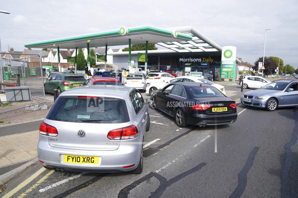 Mike Egerton Cars queue outside a petrol station in Leicester, England, Saturday Sept. 25, 2021. The haulage industry says the U.K. is short tens of thousands of truckers, due to a perfect storm of factors including the coronavirus pandemic, an aging workforce and an exodus of European Union workers following Britain’s departure from the bloc. BP and Esso shut a handful of their gas stations this week, and motorists have formed long lines as they try to fill up in case of further disruption. (Mike Egerton//PA via AP)