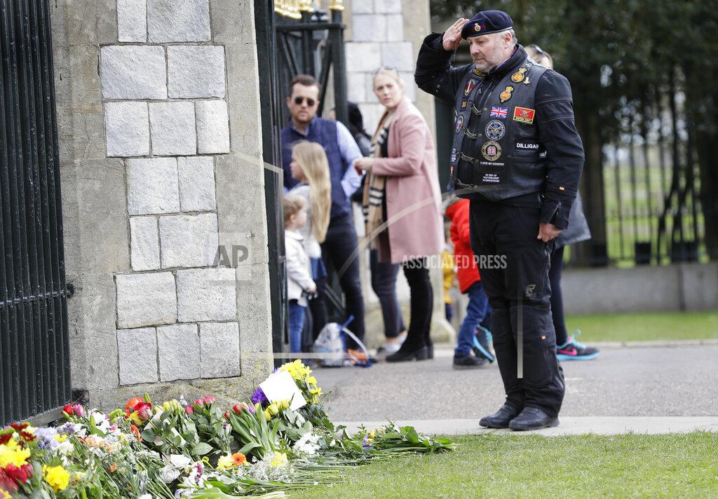 Kirsty Wigglesworth A man salutes outside Windsor Castle in Windsor, England Sunday, April 11, 2021. Britain's Prince Philip, the irascible and tough-minded husband of Queen Elizabeth II who spent more than seven decades supporting his wife in a role that mostly defined his life, died on Friday. (AP Photo/Kirsty Wigglesworth)