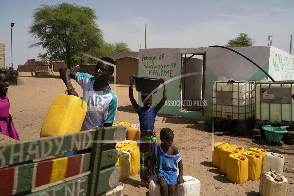 Leo Correa FILE - A girl carries a bucket of water from a community well in the village of Ndiawagne Fall, on one end of a project called "Great Green Wall" that was envisioned as a way for Africa to fight climate change, in Kebemer, Senegal, Nov. 5, 2021. A series of complex challenges, including a lack of funding and political will as well as rising insecurity linked to extremist groups al-Qaida and the Islamic State in Burkina Faso, are obstructing progress on Africa's Great Green Wall, according to experts involved in the initiative. (AP Photo/Leo Correa, File)