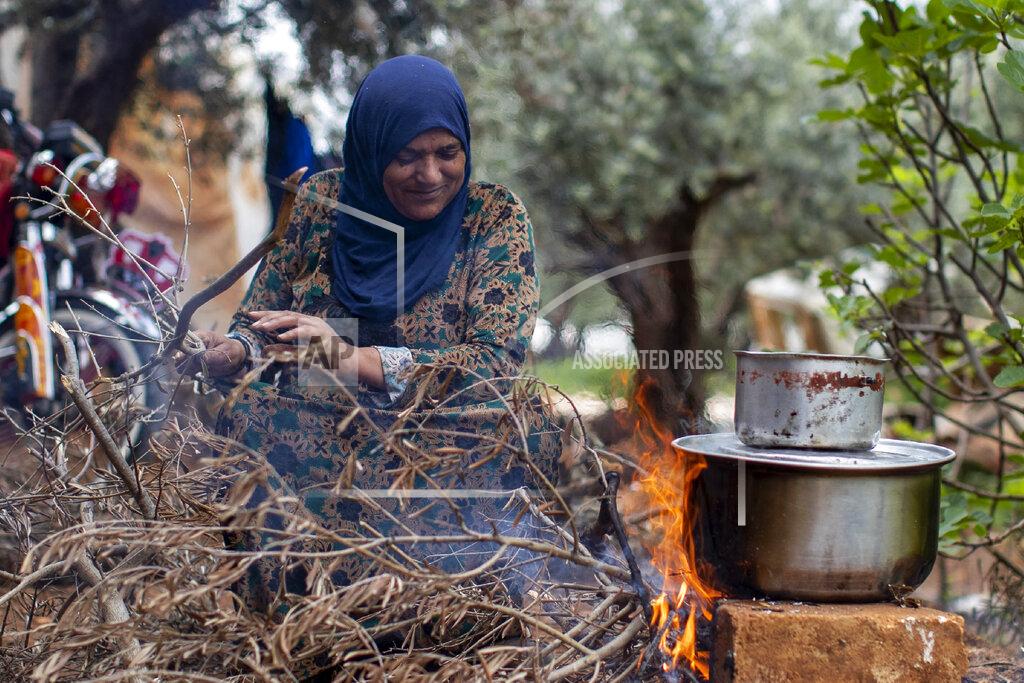 Hassan Ammar A Syrian refugee cooks food on a fire, at an informal refugee camp, in the town of Rihaniyye in the northern city of Tripoli, Lebanon, Thursday, April 8, 2021. For many Syrian refugee families in Lebanon, Ramadan comes as a hard life of displacement has gotten even harder after a pandemic year that deepened economic woes in their host country. (AP Photo/Hassan Ammar)