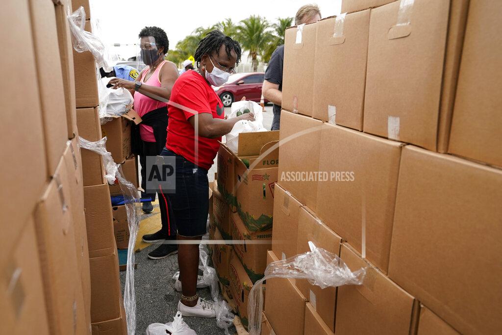 Lynne Sladky Sharon Smith-Butler, right, loads produce into a bag as she works with other volunteers at a food distribution for local residents sponsored by Feeding South Florida, Thursday, Jan. 28, 2021, in Florida City, Fla. (AP Photo/Lynne Sladky)