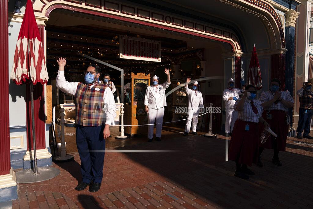 Jae C. Hong Employees wave as guests walk along Main Street USA at Disneyland in Anaheim, Calif., Friday, April 30, 2021. The iconic theme park in Southern California that was closed under the state's strict virus rules swung open its gates Friday and some visitors came in cheering and screaming with happiness. (AP Photo/Jae C. Hong)