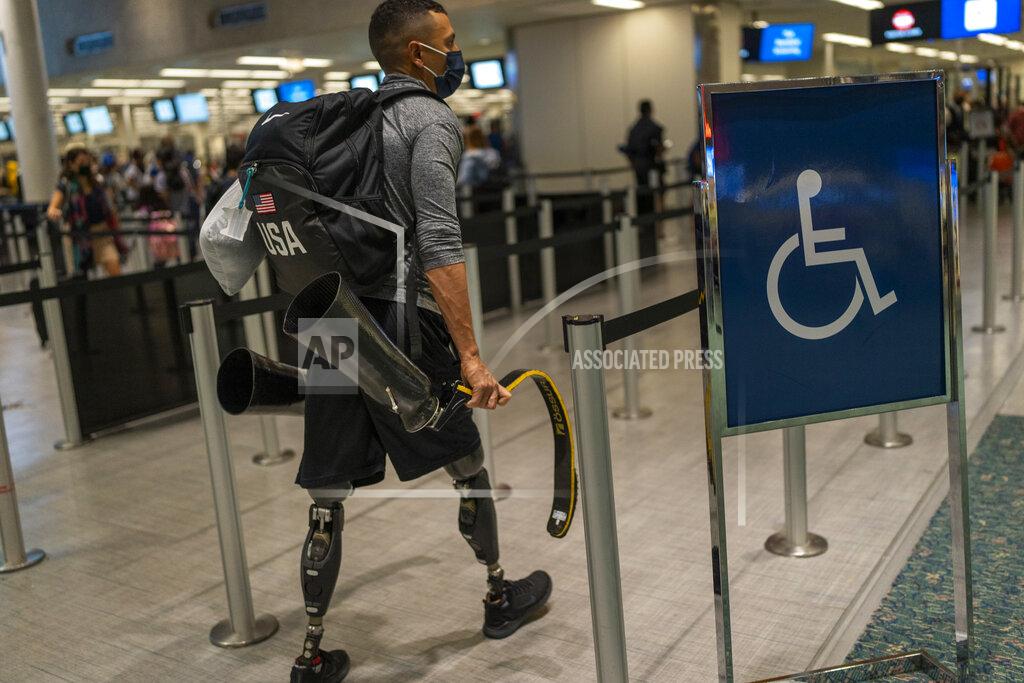 Emilio Morenatti Luis Puertas carries his prosthetic blades as he arrives at the airport in Orlando, Fla., on Monday, Aug. 9, 2021, before flying to Tokyo to take part in the Paralympics. Puertas, 34, lost both his legs in September 2006 as he patrolled a crowded Baghdad neighborhood. His legs were severed when a massive IED blasted through his armored vehicle. (AP Photo/Emilio Morenatti)
