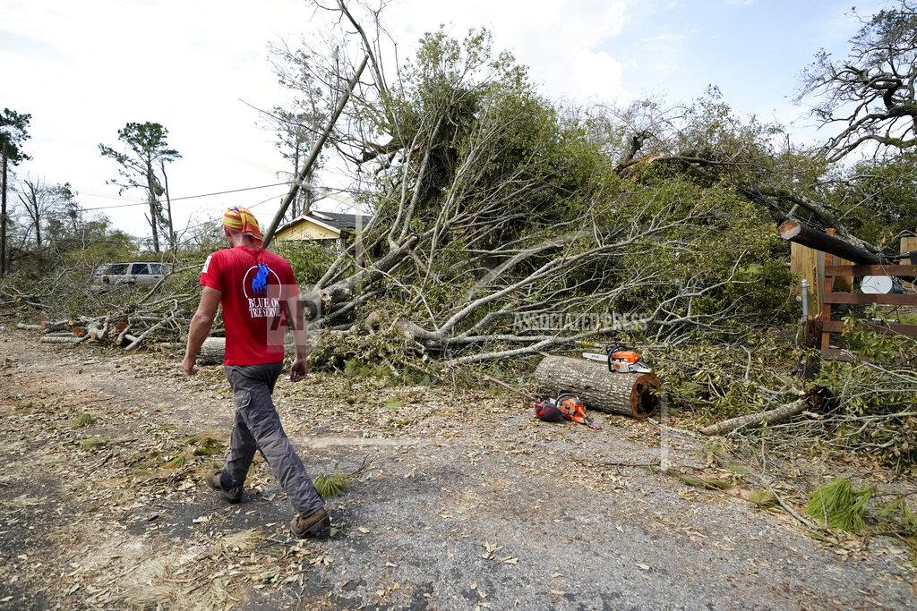 Gerald Herbert Logan Cunningham, of Canary Tree Service of Jacksonville, Fla., walks past tree debris as he waits for more equipment to arrive, in Lake Charles, La., in the aftermath of Hurricane Laura, Sunday, Aug. 30, 2020. (AP Photo/Gerald Herbert)