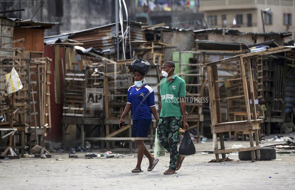 Sunday Alamba People wearing face masks walk past closed street stalls and shops due to a government ban on the operation of non-essential businesses and markets to halt the spread of the new coronavirus, in Lagos, Nigeria Thursday, March 26, 2020. (AP Photo/Sunday Alamba)