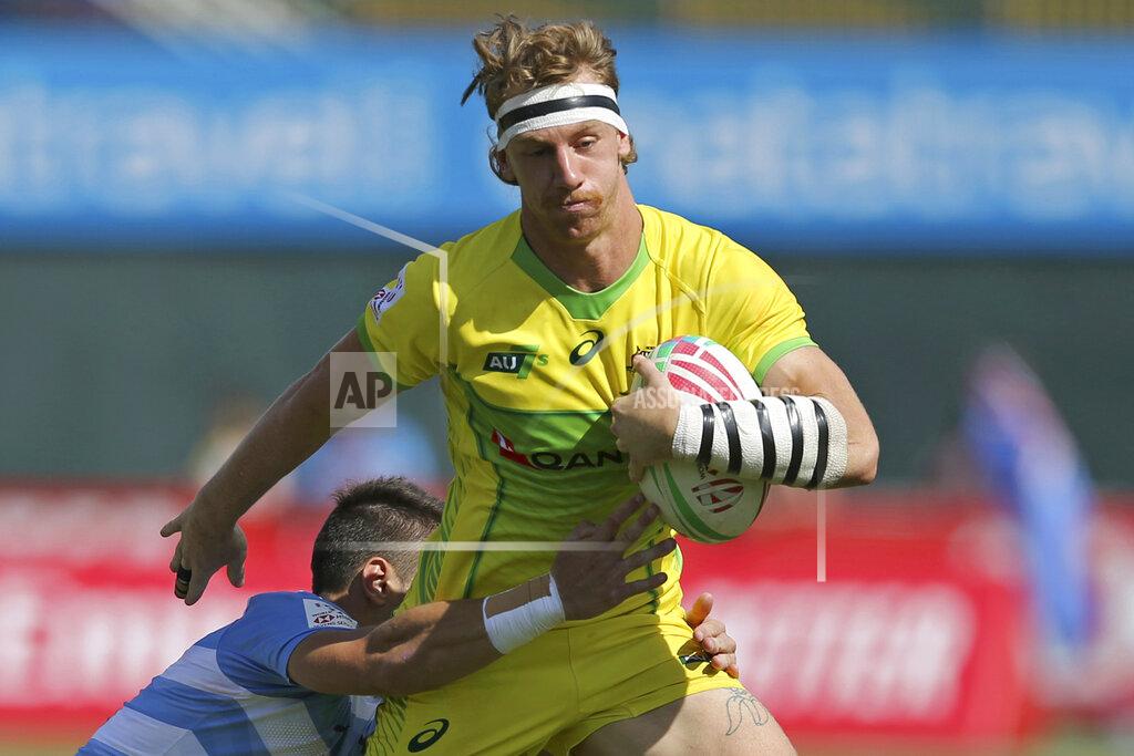 FILE - In this Dec. 1, 2018, file photo, Australia's Ben O'Donnell is tackled by Argentina's player in a quarterfinal match of the Emirates Airline Rugby Sevens in Dubai, the United Arab Emirates. O’Donnell thought his Olympic dream was over just two months ago when he injured his knee and was given no chance of recovering by July. So while the coronavirus pandemic-enforced postponement of the Tokyo Games to 2021 has been met with disappointment from the world’s leading athletes, the rugby sevens player is struggling to contain his smile. He says the Olympic postponement has "given a little opening in the door for me." (AP Photo/Kamran Jebreili, File)