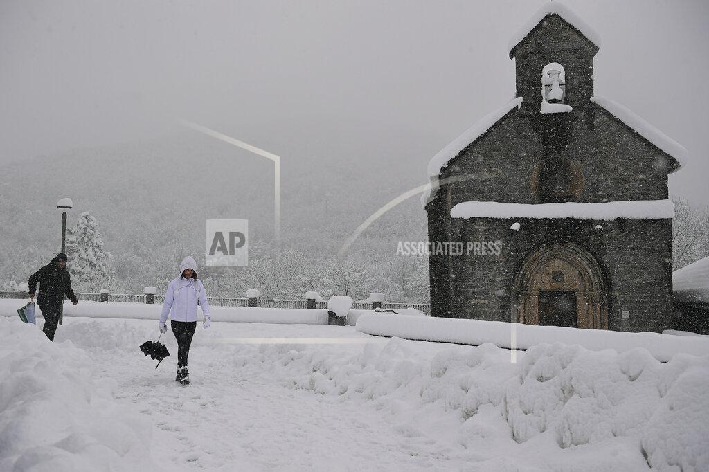 Alvaro Barrientos People walk close to an ancient church as the snow covered the landscape in small village of Roncesvalles, northern Spain, Sunday, Dec. 6, 2020. (AP Photo/Alvaro Barrientos)