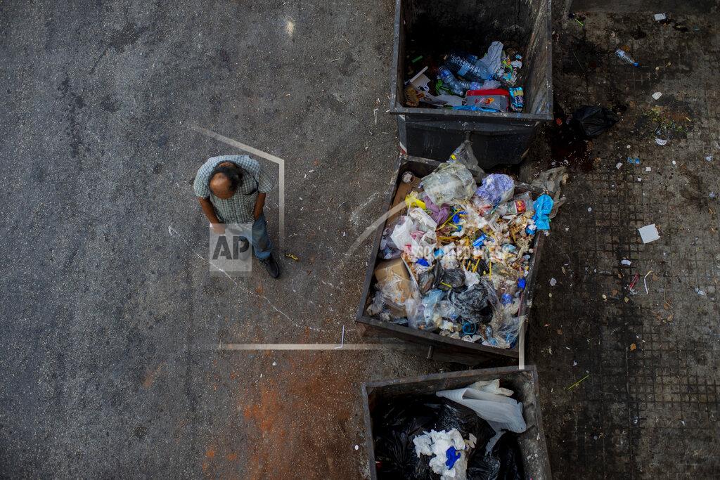 Hassan Ammar A homeless man walks next to trash dumpsters in Beirut, Lebanon, Sunday, July 12, 2020. Lebanon should quickly form a reform-minded government to carry out badly needed reforms to help get the tiny country out of its severe economic crisis where the Real GDP growth is projected to contract nearly 20% in 2020 and a crash in local currency led to triple-digit inflation rates, the World Bank said Tuesday. (AP Photo/Hassan Ammar)