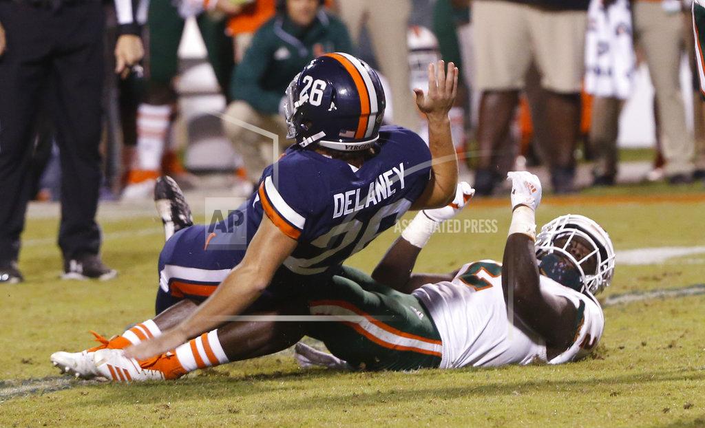 Steve Helber Virginia place kicker Brian Delaney (26) is knocked to the ground by Miami defensive back Trajan Bandy (2) as he tries to block a kick during the final moments of the second half of an NCAA college football game in Charlottesville, Va., Saturday, Oct. 13, 2018. Bandy ran into Delaney causing a roughing the kicker penalty. Virginia defeated Miami 16-13. (AP Photo/Steve Helber)
