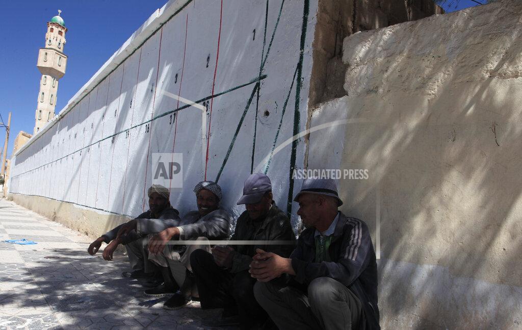 Fateh Guidoum Men sit by a wall where electoral posters for the upcoming parliamentary elections will be placed, Thursday, May 20, 2021 in Ain Ouessara, 200 kilometres (125 miles) south of Algiers. Initially planned for April 22, the the legislative election will take place on June 12, 2021 in the North African country. (AP Photo/Fateh Guidoum)