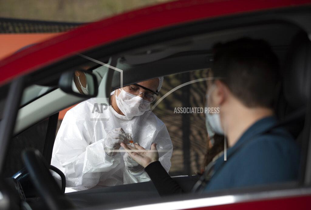 Silvia Izquierdo A health worker collects a sample from a person at a drive-thru test site for COVID-19 amid the new coronavirus pandemic in Niteroi, Brazil, Wednesday, June 3, 2020. (AP Photo/Silvia Izquierdo)