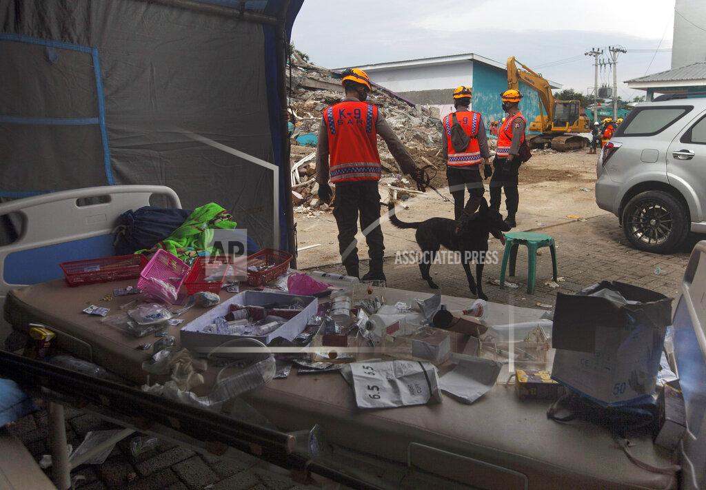 Yusuf Wahil Members of police K-9 squad lead a sniffer dog during a search for victims at a hospital building collapsed in Friday's earthquake in Mamuju, West Sulawesi, Indonesia, Sunday, Jan. 17, 2021. Rescuers retrieved more bodies from the rubble of homes and buildings toppled by the 6.2 magnitude earthquake while military engineers managed to reopen ruptured roads to clear access for relief goods. (AP Photo/Yusuf Wahil)