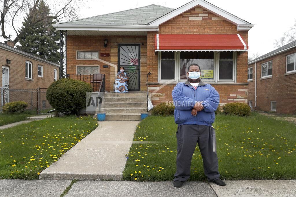 Charles Rex Arbogast Anthony Travis, who has recovered from COVID-19 and lives with his sister, Jacqueline K. Johnson, background, and an adult daughter, poses for a portrait outside his Riverdale, Ill., home on Thursday, April 23, 2020. Travis, who's diabetic, has high blood pressure and is a cancer survivor, must self isolate within the home as a matter of taking care of one another. (AP Photo/Charles Rex Arbogast)