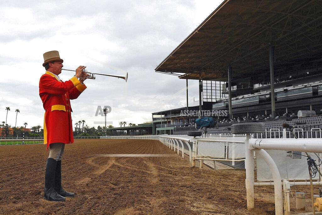Mark J. Terrill Bugler Jay Cohen plays "First Call" as he calls the riders to post for the first race at Santa Anita Park to empty stands Saturday, March 14, 2020, in Arcadia, Calif. While most of the sports world is idled by the coronavirus pandemic, horse racing runs on. (AP Photo/Mark J. Terrill)