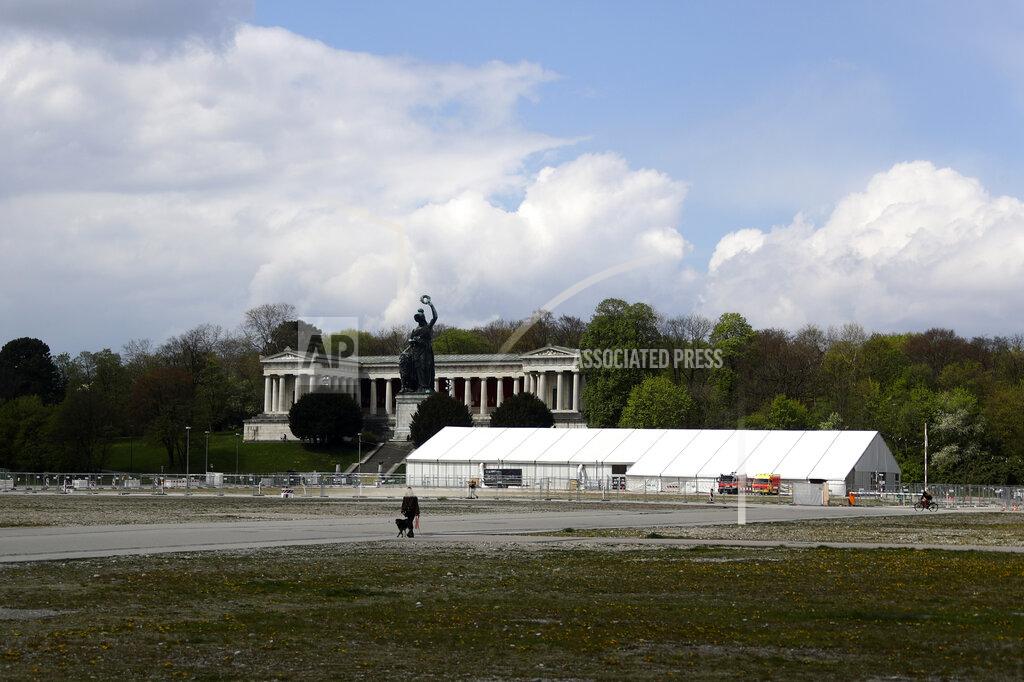 A woman and her dog walk by the 'Oktoberfest' beer festival area 'Theresienwiese' in front of the Bavaria statue and a corona test centre in Munich, Germany, Monday, May 3, 2021. The world's largest beer festival 'Oktoberfest' was cancelled last year due to the coronavirus outbreak. (AP Photo/Matthias Schrader)