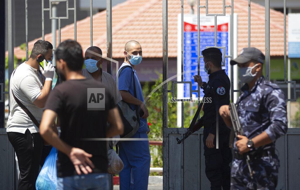 Khalil Hamra A Palestinian medic wears a face mask as he passes by Hamas police officers guarding the entrance of the Shifa Hospital after coronavirus cases were discovered in the hospital, in Gaza City, Wednesday, Aug. 26, 2020. Gaza health officials have reported the first death from COVID-19 since authorities detected the first local cases of the coronavirus earlier this week. (AP Photo/Khalil Hamra)