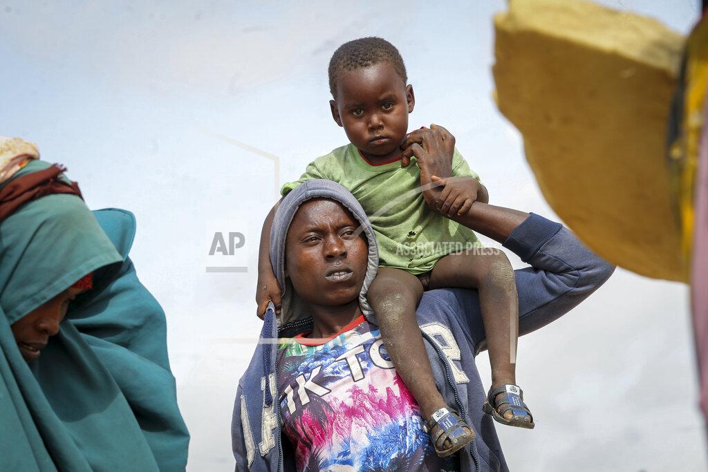 Farah Abdi Warsameh A Somali man carries a child as he and others who fled drought-stricken areas arrive at a makeshift camp for the displaced on the outskirts of Mogadishu, Somalia Thursday, June 30, 2022. The war in Ukraine has abruptly drawn millions of dollars away from longer-running humanitarian crises and Somalia is perhaps the most vulnerable as thousands die of hunger amid the driest drought in decades. (AP Photo/Farah Abdi Warsameh)