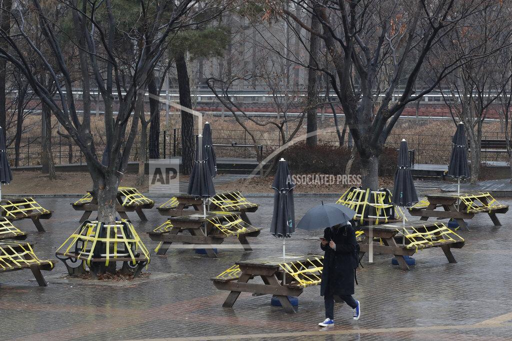 Lee Jin-Man A man wearing a face mask as a precaution against the coronavirus walks past benches and tables taped for social distancing in Seoul, South Korea, Thursday, Jan. 21, 2021. (AP Photo/Lee Jin-man)