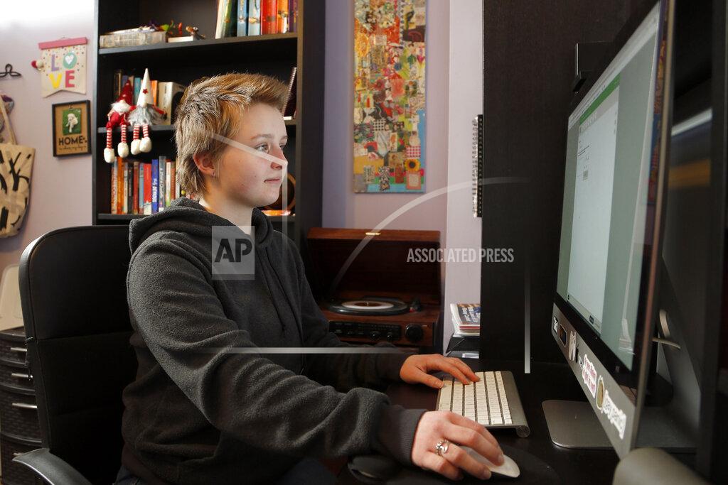 Graciela Leahy, 13, an eighth grader at Ohio's Columbus Gifted Academy, works on her computer in her bedroom, in Columbus, Ohio, Feb. 23, 2021, to begin a stretch of nearly six straight hours at her desk. A year later in the pandemic, the unplanned experiment with distance learning continues for thousands of students like Leahy who have yet to set foot back in classrooms. (AP Photo/Jay LaPrete)