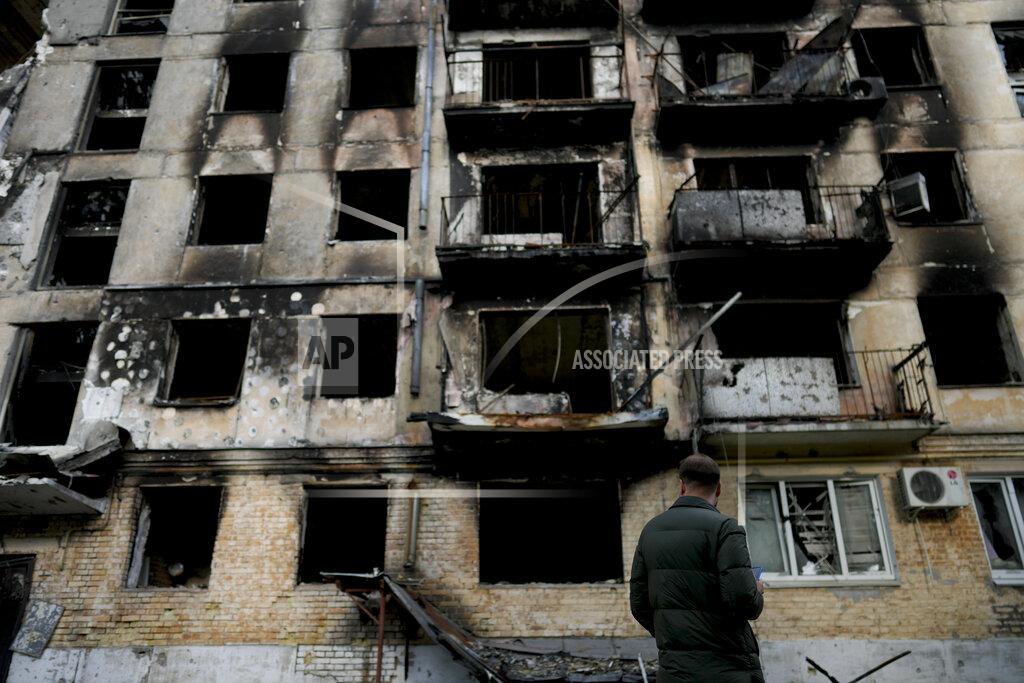 Natacha Pisarenko A man stands in front of a damage building ruined by attacks in Hostomel, outskirts Kyiv, Ukraine, Thursday, May 26, 2022. (AP Photo/Natacha Pisarenko)