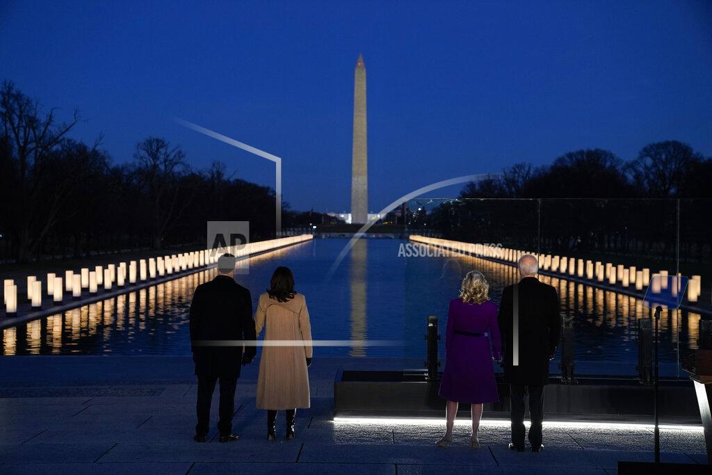 With the Washington Monument in the background, President-elect Joe Biden with his wife Jill Biden and Vice President-elect Kamala Harris with her husband Doug Emhoff listen as Yolanda Adams sings "Hallelujah" during a COVID-19 memorial, with lights placed around the Lincoln Memorial Reflecting Pool, Tuesday, Jan. 19, 2021, in Washington. (AP Photo/Evan Vucci)