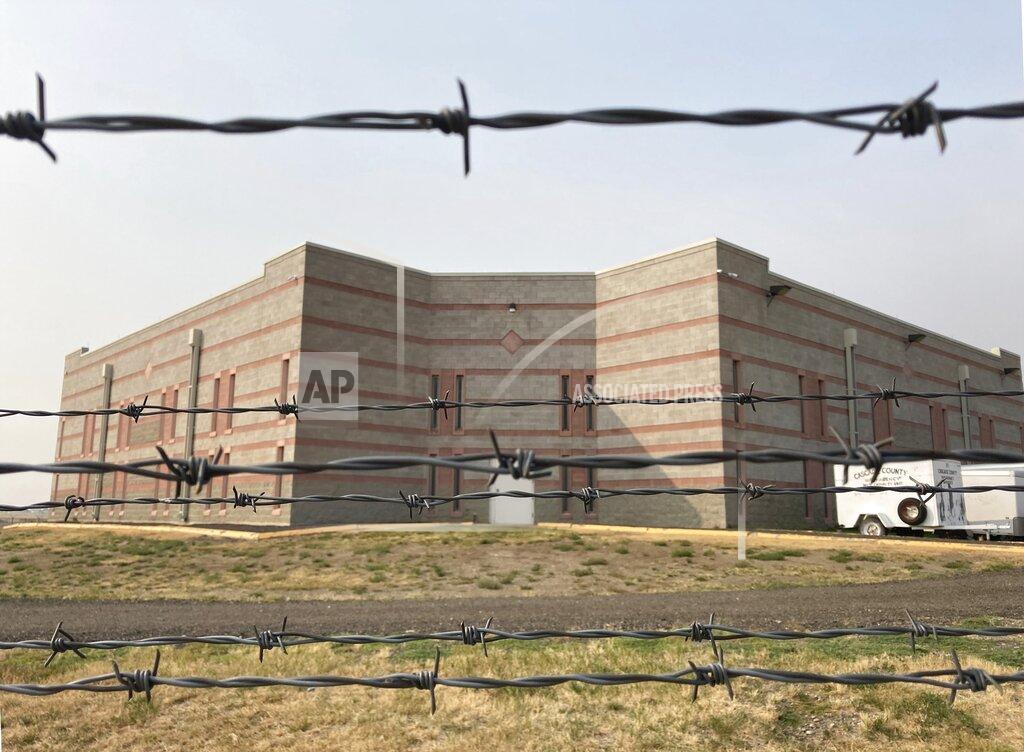 Matt Volz In this Sept. 18, 2020 photo, the Cascade County Detention Center is seen through barbed wire fencing in Great Falls, Mont. The jail is one of three in Montana experiencing COVID-19 outbreaks, which Sheriff Jesse Slaughter blames on overcrowding and too many inmates awaiting transfer to the state prison. (Matt Volz/Kaiser Health News via AP)