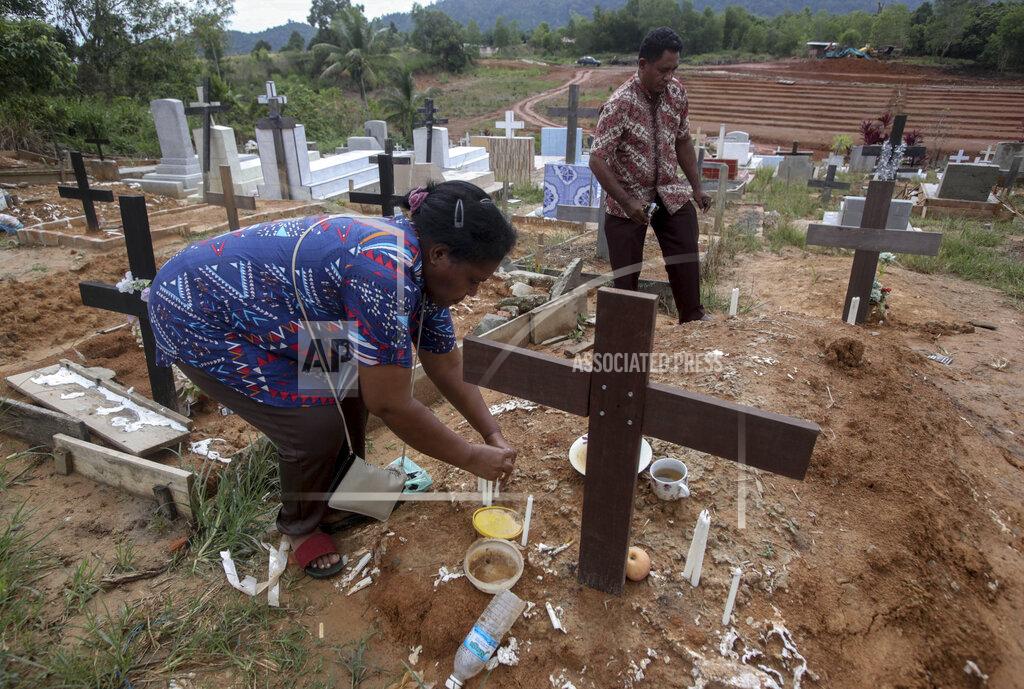 Binsar Bakkara An Indonesian migrant worker places candles on the grave of her husband who worked on a Malaysian palm oil plantation in Sabah, Malaysia, on Sunday, Dec. 9, 2018. As global demand for palm oil surges, plantations are struggling to find enough laborers, frequently relying on brokers who prey on the most at-risk people. The bodies of migrants who die are sometimes not sent home. (AP Photo/Binsar Bakkara)
