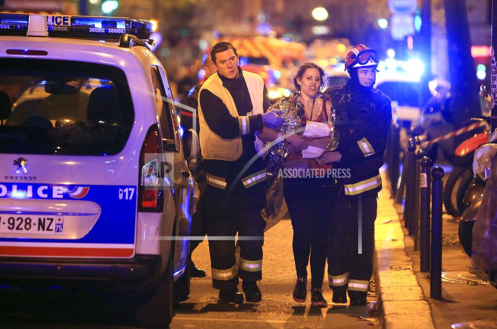 Thibault Camus FILE - In this Nov. 13, 2015, file photo, rescue workers help a woman after an attack by Islamic State militants, outside the Bataclan theater in Paris. On Nov. 13, 2015, a cell of nine Islamic State militants armed with automatic rifles and explosive vests left a trail of dead and injured at the national stadium, Paris bars and restaurants and the Bataclan concert hall. Nearly all the attackers were from France or Belgium, as were the cell's 10th member — the only one still alive. He is the chief defendant among 20 people charged in a trial that is expected to last nine months. (AP Photo/Thibault Camus, File)