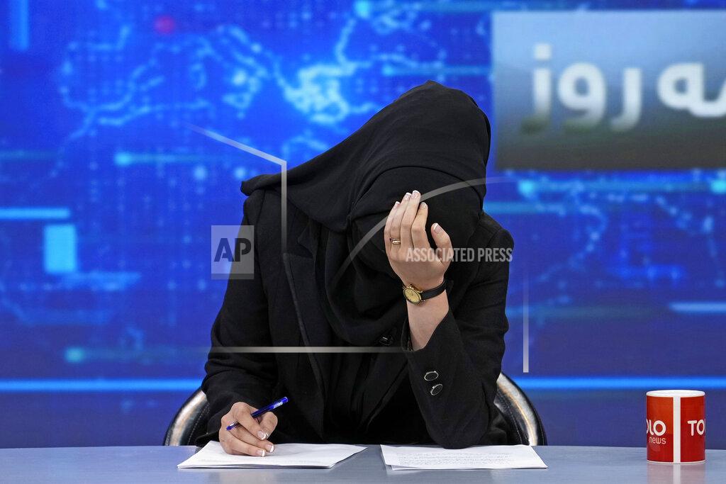 Ebrahim Noroozi TV anchor Khatereh Ahmadi bows her head while wearing a face covering as she reads the news on TOLO NEWS, in Kabul, Afghanistan, Sunday, May 22, 2022. Afghanistan's Taliban rulers have begun enforcing an order requiring all female TV news anchors in the country to cover their faces while on-air. The move Sunday is part of a hard-line shift drawing condemnation from rights activists. (AP Photo/Ebrahim Noroozi)