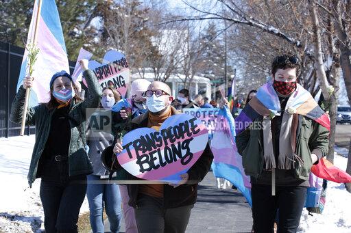 FILE - Advocates for transgender people march from the South Dakota governor's mansion to the Capitol in Pierre, S.D., on March 11, 2021. A South Dakota legislative committee on Friday, Jan. 14, 2022 approved a bill championed by Gov. Kristi Noem to ban transgender women and girls from participating in school sports leagues that match their gender identity. (AP Photo/Stephen Groves, File)