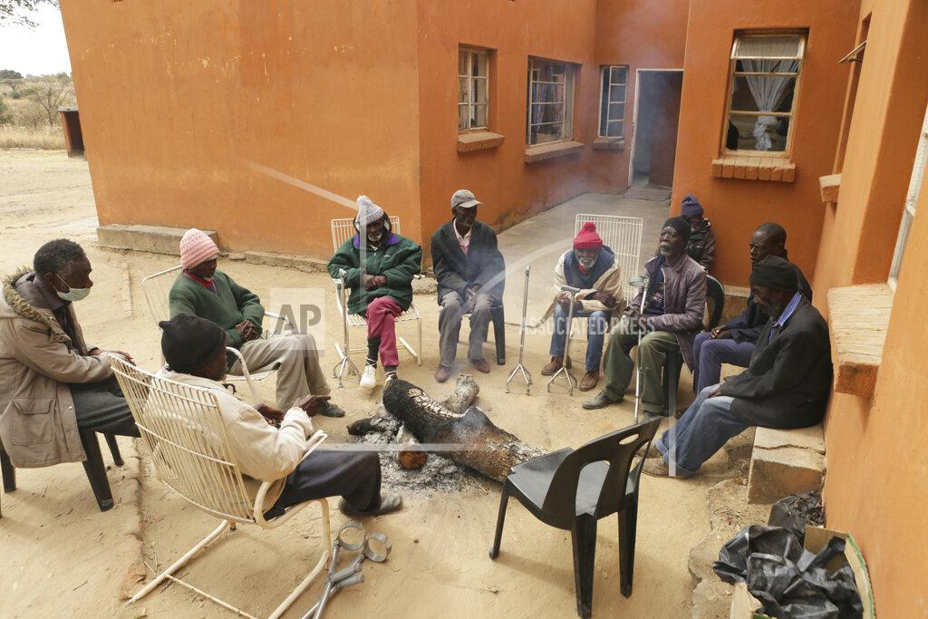 Tsvangirayi Mukwazhi Elderly men gather around a fire at Melfort Old People's home on the outskirts of Harare, Zimbabwe, Sunday, July 25, 2021. The economic ravages of COVID-19 are forcing some families in Zimbabwe to abandon the age old tradition of taking care of the elderly. Zimbabwe's care homes have experienced a 60% increase in admissions since the outbreak of the pandemic in March last year. (AP Photo/Tsvangirayi Mukwazhi)