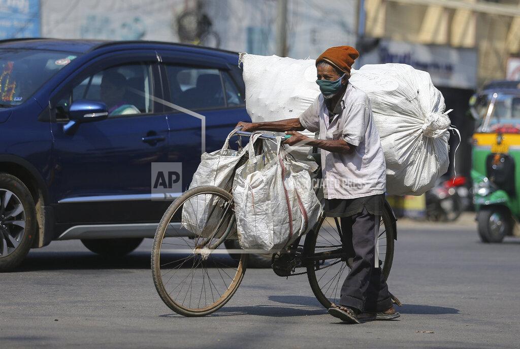 Mahesh Kumar A An Indian man wearing face mask as a precaution against the coronavirus pushes his bicycle with load in Hyderabad, India, Thursday, Dec. 17, 2020. (AP Photo/Mahesh Kumar A.)