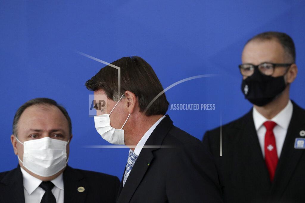 Brazilian President Jair Bolsonaro walks past his Health Minister Eduardo Pazuello, left, and President of the Sanitary Agency Antonio Barra Torres before a ceremony to sign a law that expands the federal government's ability to acquire COVID-19 vaccines, at Planalto presidential palace in Brasilia, Brazil, Wednesday, March 10, 2021. (AP Photo/Eraldo Peres)