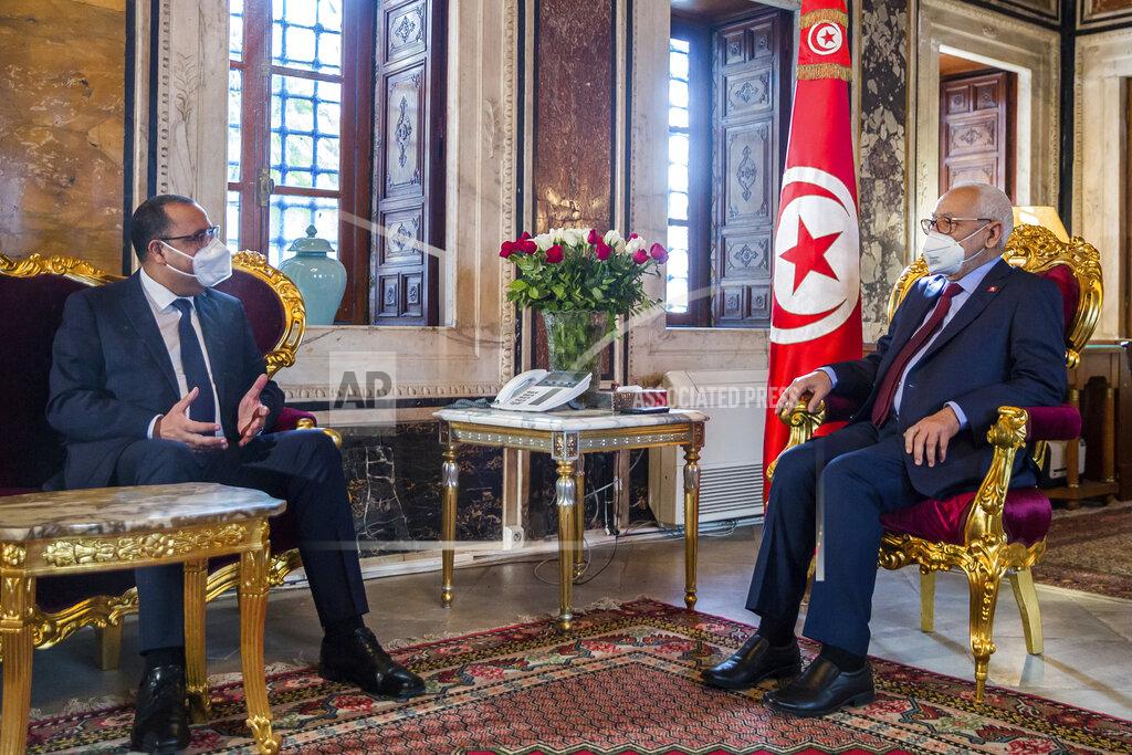 Hassene Dridi Tunisian Prime Minister Hichem Mechichi, left, talks with housespeaker Rached Ghannouchi, before the government faces a confidence vote, Tuesday, Jan.26, 2021 at the Parliament in Tunis. Tunisians are marching on their heavily guarded parliament Tuesday as lawmakers vote on a new government, after a week of youth protests and riots over poverty and lack of jobs that left one young demonstrator dead and hundreds jailed. Prime Minister Hichem Mechichi announced a government reshuffle last week in the midst of the unrest. (AP Photo/Hassene Dridi)