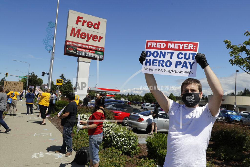 Ted S. Warren Sherman Jenne, right, a cashier at the Fred Meyer grocery store in Burien, Wash., takes part in a protest outside the store against Fred Meyer's parent company Kroger, Friday, May 15, 2020, that was organized by the United Food and Commercial Workers International Union. Kroger officials have said they are ending the additional $2 hourly "hero pay" bonus that had been paid to workers since late March during the coronavirus pandemic. The company said Friday it will now offer one-time bonus payments of $400 and $200 for full- and part-time employees to be paid in two installments. (AP Photo/Ted S. Warren)