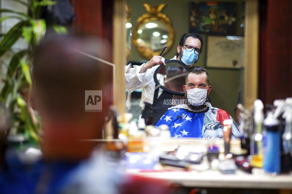 Christopher Dolan FILE - In this Friday, June 26, 2020 file photo, Barber Mike McAndrew holds a mirror as customer Rob Verrastro looks at his new haircut at Three Saints Barbershop and Shave Parlor in Jessup, Pa. Restaurants, retailers and salons are desperately trying to stay afloat as the U.S. economy reopens in fits and starts after months in a coronavirus lockdown. But billions of dollars allocated by Congress as a lifeline to those very businesses are about to be left on the table when the government's Paycheck Protection Program stops accepting applications for loans Tuesday, June 29. (Christopher Dolan/The Times-Tribune via AP, File)