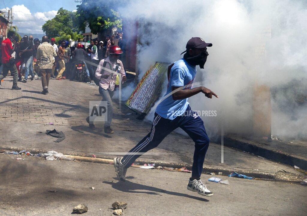 Dieu Nalio Chery Protesters run from tear gas launched by police to disperse protesters demanding the resignation of President Jovenel Moise in Port-au-Prince, Haiti, Saturday, Oct. 17, 2020. The country is currently experiencing a political impasse without a parliament and is now run entirely by decree under Moise. ( AP Photo/Dieu Nalio Chery)