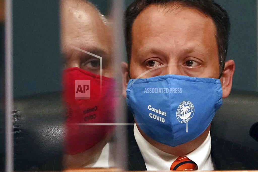 Joe Cavaretta The reflection of the Palm Beach County Vice-Mayor Robert Weinroth, left, is seen in a plexiglass coronavirus shield next to Mayor Dave Kerner during a Commission hearing on a possible easing of COVID-19 restrictions to phase two, Tuesday, Sept. 1, 2020, in West Palm Beach, Fla. (Joe Cavaretta/South Florida Sun-Sentinel via AP)