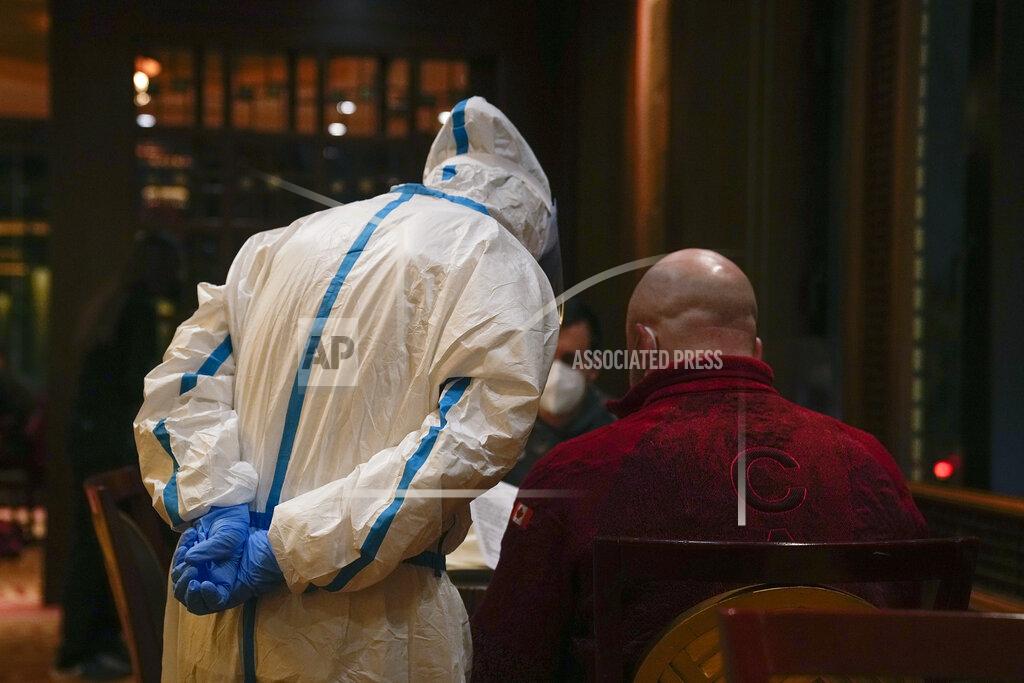 A server wearing protective gear takes an order from a member of the Canadian Olympic team in a restaurant inside the Shangri-La Hotel at the 2022 Winter Olympics, Wednesday, Feb. 16, 2022, in Beijing. (AP Photo/Jae C. Hong)