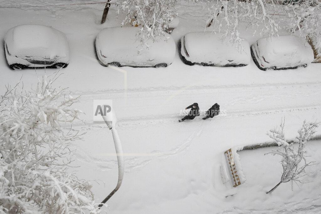 Paul White Two men walk slowly in the middle of a street after a heavy snowfall in Madrid, Spain, Saturday, Jan. 9, 2021. Spain is on high alert as a cold snap is covering much of the country with snow disrupting road, sea, rail and air traffic with the capital, Madrid enduring what the city's mayor described as "the worst storm in 80 years." (AP Photo/Paul White)