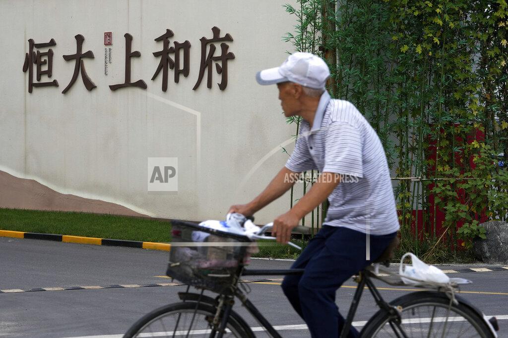 Andy Wong A man bicycles past an Evergrande new housing development in Beijing, Wednesday, Sept. 15, 2021. One of China's biggest real estate developers is struggling to avoid defaulting on billions of dollars of debt, prompting concern about the broader economic impact and protests by apartment buyers about delays in completing projects. Rating agencies say Evergrande Group appears likely to be unable to repay all of the 572 billion yuan ($89 billion) it owes banks and other bondholders. That might jolt financial markets, but analysts say Beijing is likely to step in to prevent wider damage. (AP Photo/Andy Wong)
